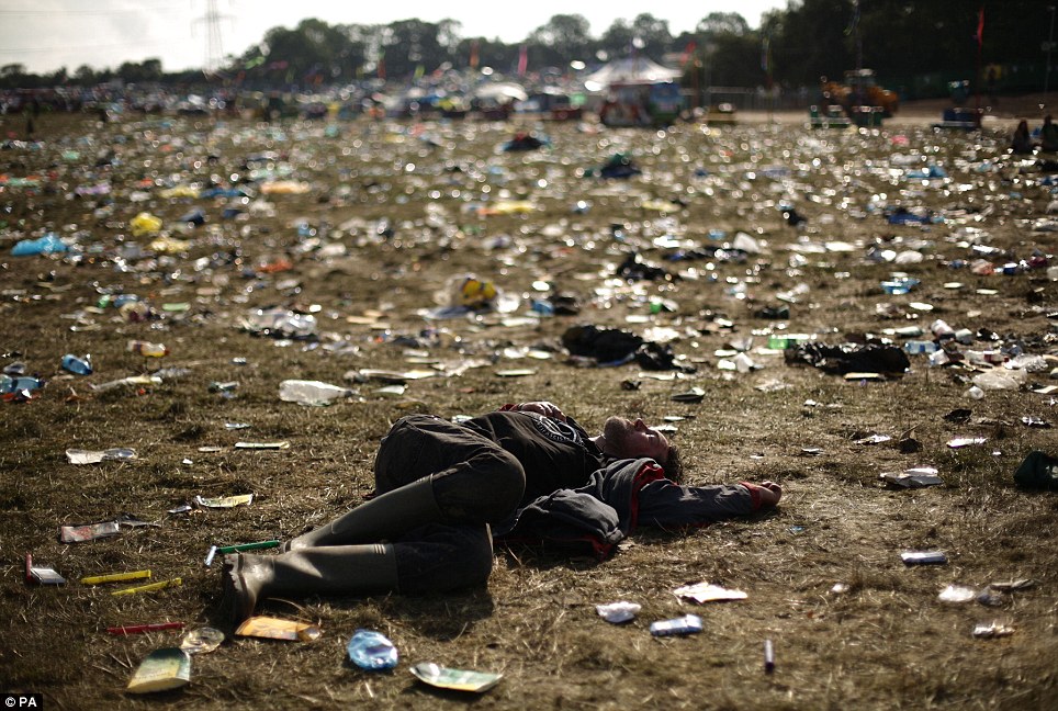 Lying down: A festival goer is flat out on the ground as the clean up operation begins around the Pyramid Stage, at the Glastonbury Festival